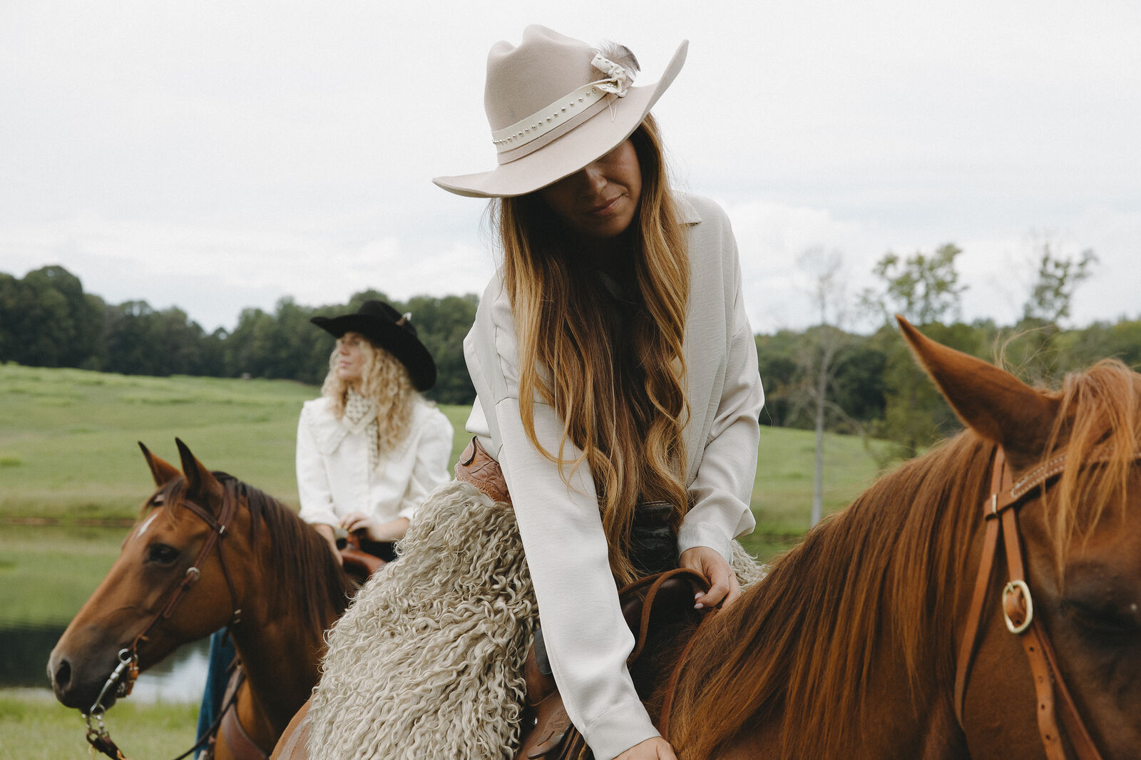 Two women on horseback in a green pasture